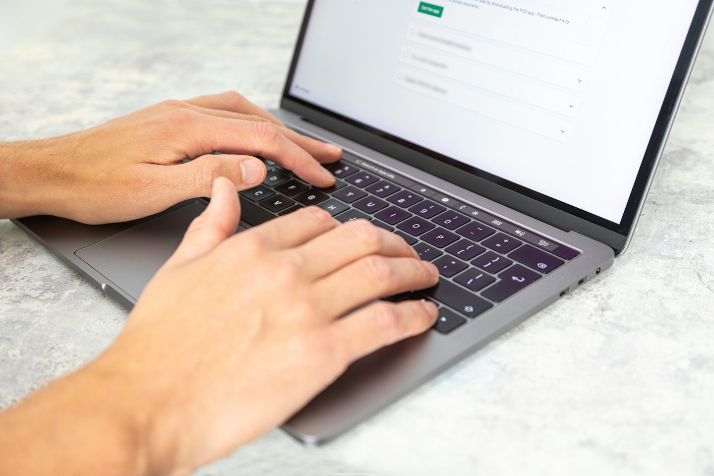 Hände tippen auf einer Laptop-Tastatur mit hellem Bildschirm.